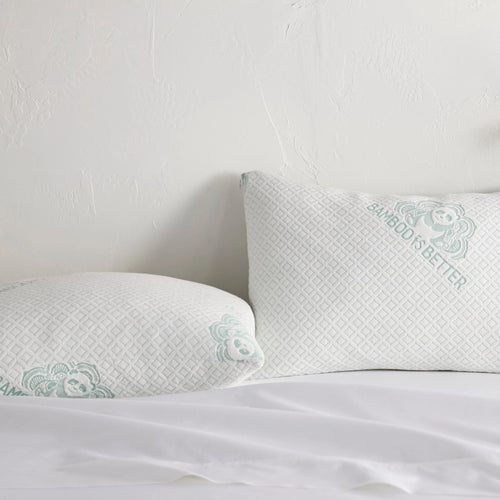 Two white pillows with a textured pattern on a bed against a light gray wall.