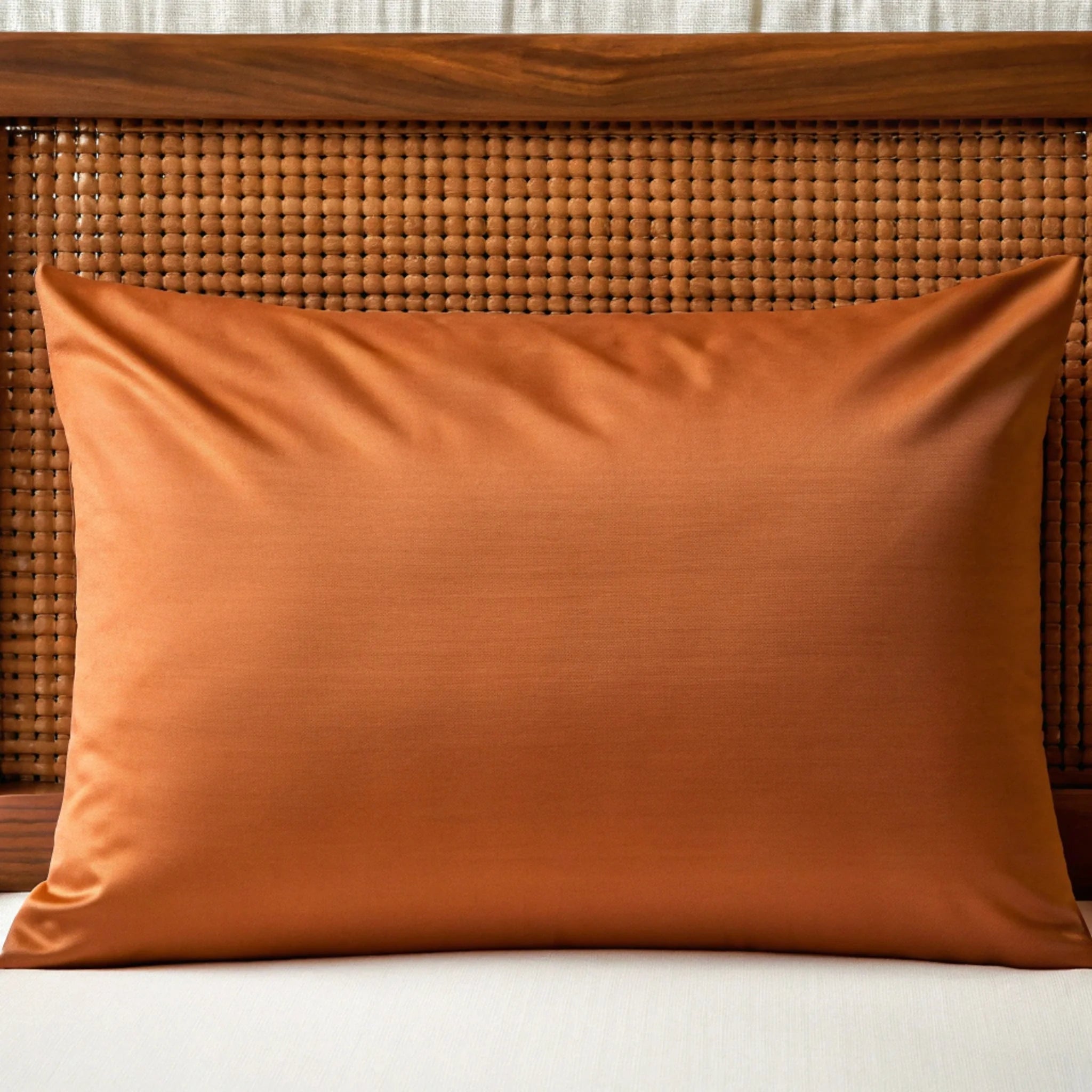 Orange pillow on a wicker chair with a white cushion