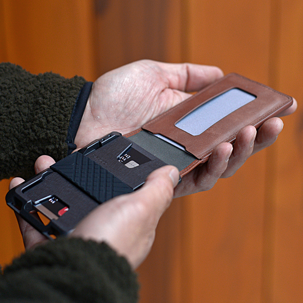 Person holding a smartphone with a leather case against an orange background